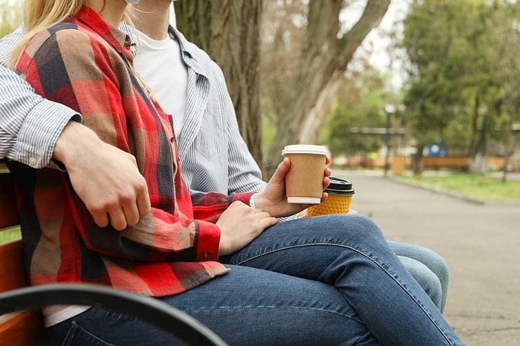 Couple sitting in the park and drink coffee