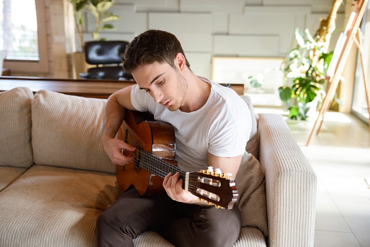 man playing guitar on couch